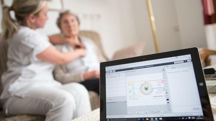 Eine Pflegerin legt einer Bewohnerin im Rahmen einer elektronischen Visite in einer Seniorenresidenz ein EKG-Gerät an.