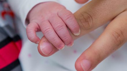 Die Hand einer Mutter wird von ihrem Kind umfasst.