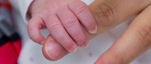 Die Hand einer Mutter wird von ihrem Kind umfasst.