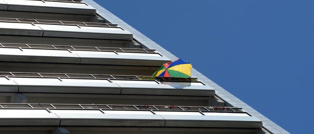 Ein bunter Sonnenschirm in der oberen Etage eines Wohnhochhauses in Berlin.