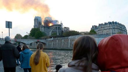 Menschen schauen auf den Brand der Kathedrale Notre-Dame in Paris.
