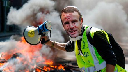 Ein Demonstrant in Paris mit einer Maske von Präsident Macron 