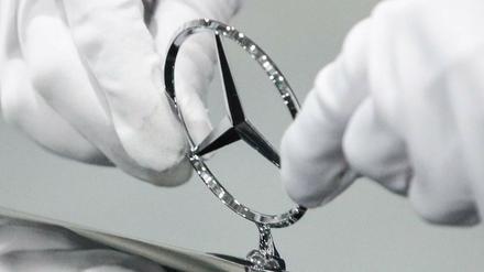 Sauber bleiben: Ein Fabrikarbeiter justiert den Stern an einem neuen Mercedes.