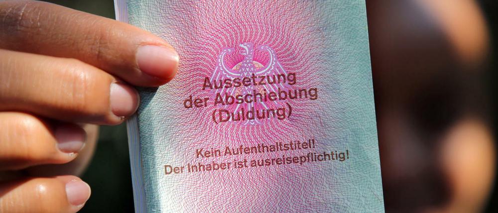 Eine junge Frau hält einen Ausweis für Flüchtlinge in der Hand.
