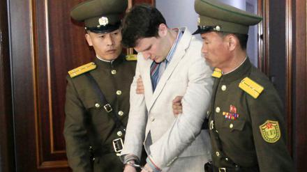 Der US-Bürger Otto Warmbier (M) wird am 16.03.2016 in einem Gericht in Pjöngjang (Nordkorea) von zwei nordkoreanischen Polizisten eskortiert.