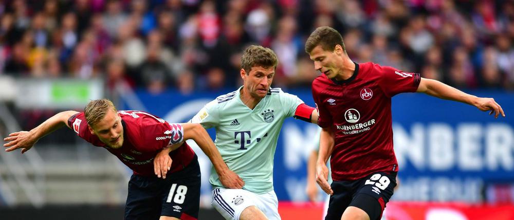 28.04.2019, Bayern, Nürnberg: Fußball: Bundesliga, 1. FC Nürnberg - Bayern München, 31. Spieltag im Max-Morlock-Stadion. Der Münchner Thomas Müller (M) versucht sich gegen die Nürnberger Hanno Behrens (l) und Patrick Erras durchzusetzen. Foto: Matthias Merz/dpa - WICHTIGER HINWEIS: Gemäß den Vorgaben der DFL Deutsche Fußball Liga bzw. des DFB Deutscher Fußball-Bund ist es untersagt, in dem Stadion und/oder vom Spiel angefertigte Fotoaufnahmen in Form von Sequenzbildern und/oder videoähnlichen Fotostrecken zu verwerten bzw. verwerten zu lassen. +++ dpa-Bildfunk +++