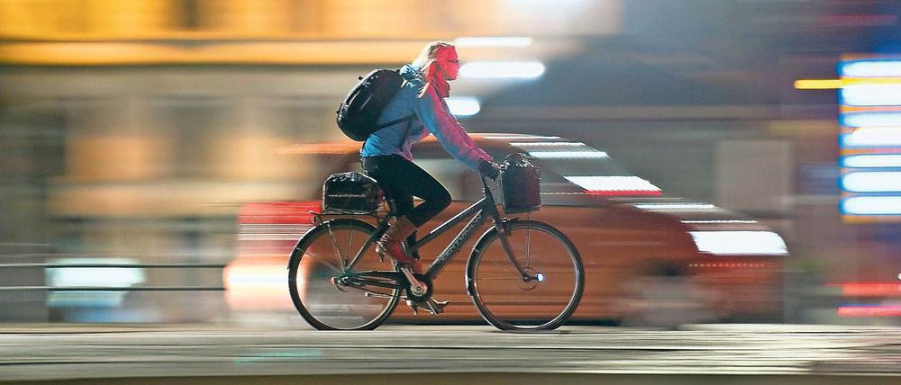Eine Radfahrerin fährt durch das nächtliche Kopenhagen.