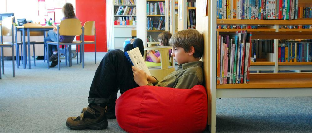Kinder sitzen in einer Bibliothek auf Sitzsäcken und lesen.