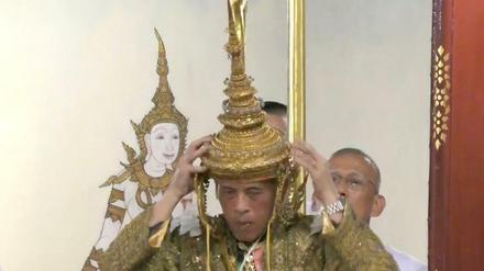 Maha Vajiralongkorn setzt sich die Krone auf.