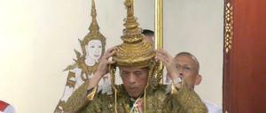 Maha Vajiralongkorn setzt sich die Krone auf.