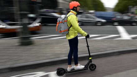 Ein Frau fährt mit einem E-Tretroller auf einem Fahrradweg in Brüssel. 
