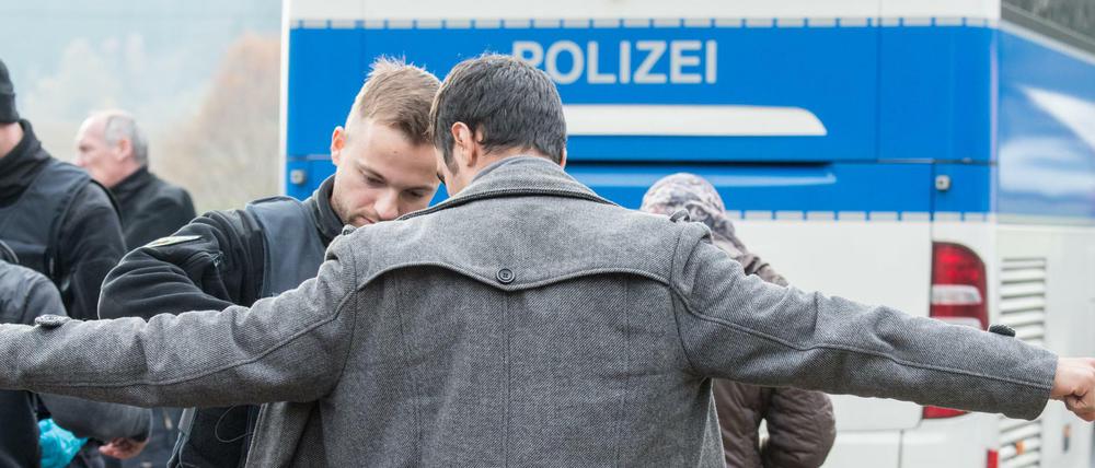 Ein Flüchtling wird am 04.11.2015 an der deutsch-österreichischen Grenze nahe Wegscheid (Bayern) von einem Bundespolizisten durchsucht. 