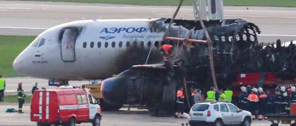 Der ausgebrannte Superjet wird mit einem Kran vom Flughafen entfernt. 