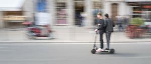 Zwei Personen fahren auf einem ausgeliehenen E-Scooter.