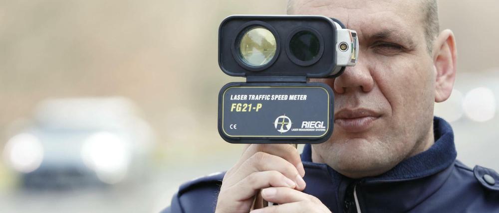 Polizist mit Tempomessgerät.
