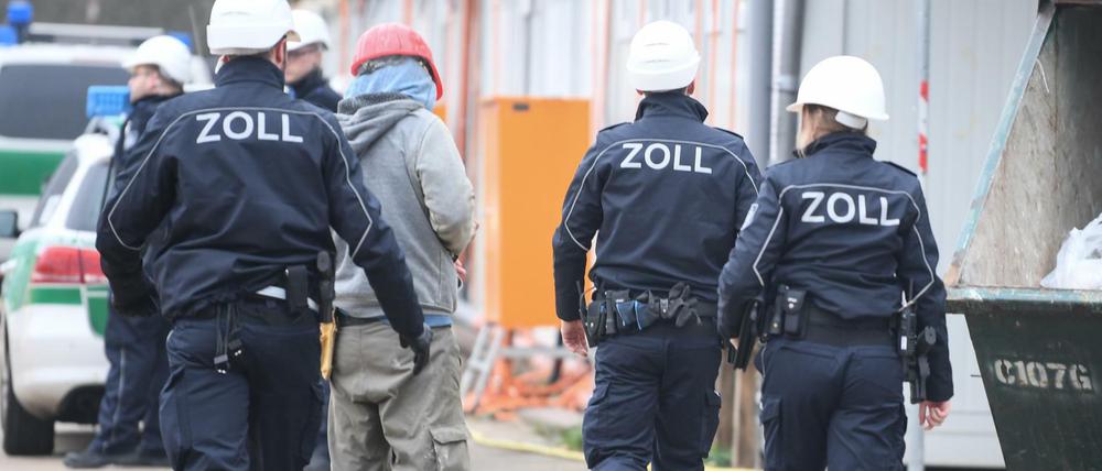Beamte des Zoll kontrollieren einen Bauarbeiter.