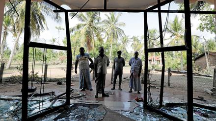 Unruhen aus Sri Lanka: Muslime stehen vor einer von Randalierern demolierten Moschee. 
