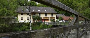 Blick durch das Geländer einer Brücke über die Ilz auf die Pension in Passau, in der drei Leichen gefunden wurden. 