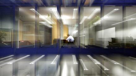 Ein Angestellter sitzt nach Einbruch der Dunkelheit noch in einem Büro am Schreibtisch und arbeitet (Archiv)