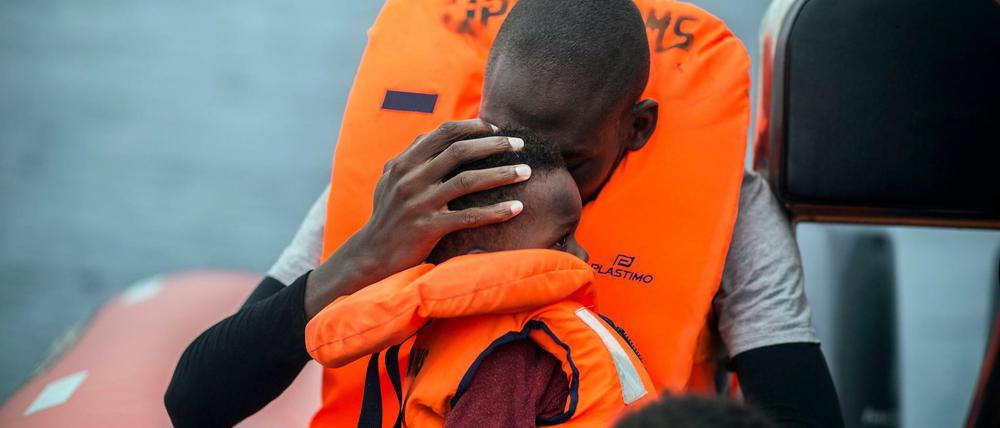 Ein Mann hält seinen Sohn im Arm, nachdem er gemeinsam mit anderen Flüchtlingen von Helfern der spanischen Nichtregierungsorganisation Pro Activa Open Arms von ihrem Schlauchboot im Mittelmeer gerettet wurde. Der von den UN-Mitgliedstaaten im Juli 2018 beschlossene UN-Migrationspakt wurde im Dezember 2018 in Marokko angenommen. 