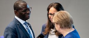 Bundeskanzlerin Angela Merkel (CDU, r) unterhält sich bei der Sitzung des Bundestages mit den SPD-Bundestagsabgeordneten Karamba Diaby und Yasmin Fahimi.