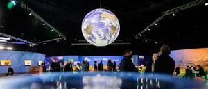 ARCHIV - 13.11.2021, Großbritannien, Glasgow: Menschen stehen bei der UN-Klimakonferenz COP26 unter einem Globus.  (zu dpa "Sturgeon: Keine Anzeichen für Corona-Ausbrüche bei Klimagipfel") Foto: Christoph Soeder/dpa +++ dpa-Bildfunk +++