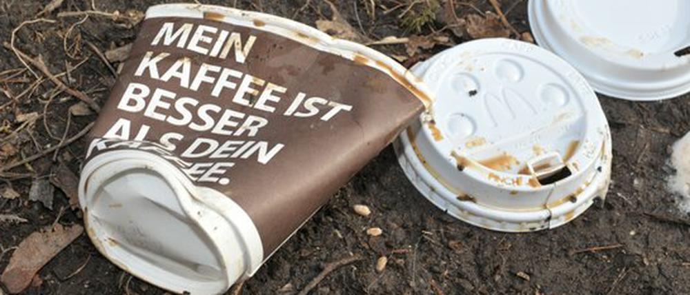 Weggeworfene Einweg-Kaffeebecher im Gras.