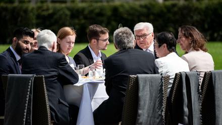 Bundespräsident Frank-Walter Steinmeier (3.v.r) unterhält sich bei der Geburtstagskaffeetafel zum 70. Jahrestag des Grundgesetzes im Park von Schloss Bellevue mit Gästen.
