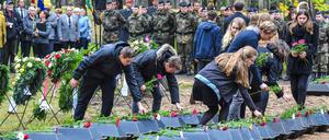 Schüler legen Blumen auf kleine Särge mit sterblichen Überresten von deutschen Soldaten auf dem Waldfriedhof in Halbe (Brandenburg) nieder. 