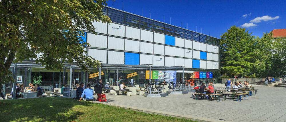 Studierende sitzen vor einem Gebäude der TU Chemnitz