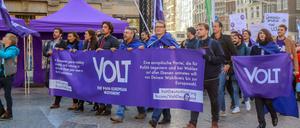 Mitglieder und Anhänger der proeuropäischen Partei Volt ziehen mit Flaggen und Bannern in Amsterdam durch eine Straße. 