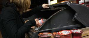 Eine Jugendliche in Berlin sucht nachts in einer Abfalltonne nach verwertbaren Lebensmitteln.