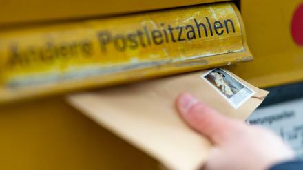 Ein Mann wirft einen Brief in einen Briefkasten. Das Briefporto soll zum 1. Juli steigen.