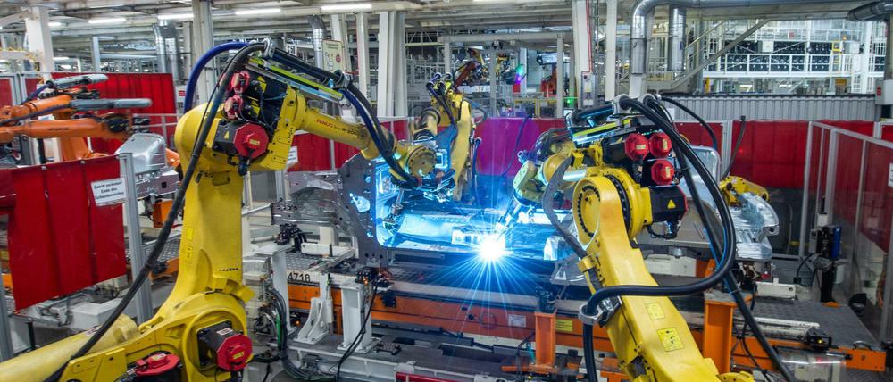 Ob die Beschäftigungsgarantie bis 2029 auch für Kollege Roboter gilt? Schweißroboter am Unterbau eines neuen Volkswagens.