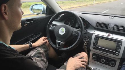 Fahrer eines autonom fahrenden Autos, Hände im Schoß.