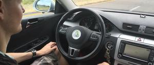 Fahrer eines autonom fahrenden Autos, Hände im Schoß.