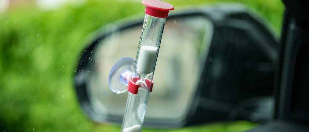 Ein Blick auf eine Sanduhr an der Scheibe eines parkenden Autos. 
