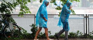 06.06.2019, Berlin: Eine Frau und ein Mann laufen in blauen Regencapes durch den Regen. Foto: Lisa Ducret/dpa +++ dpa-Bildfunk +++