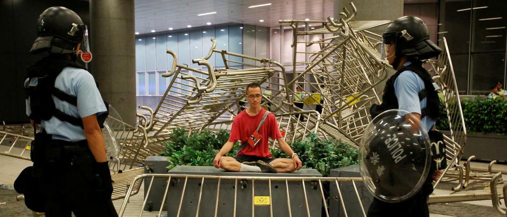 Nach den gewaltsamen Auseinandersetzungen am Ende der Demonstration in Hongkong stehen zwei Polizisten vor einem Demonstranten.