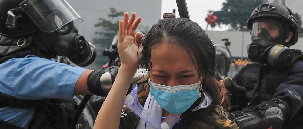 Hongkonger Polizisten drücken eine Demonstrantin gegen eine Absperrung.
