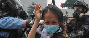 Hongkonger Polizisten drücken eine Demonstrantin gegen eine Absperrung. 