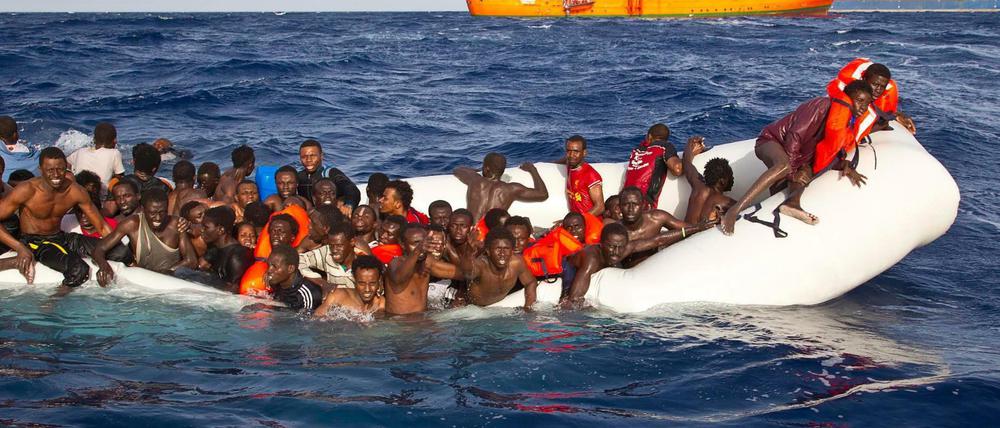 Flüchtlinge sitzen auf dem Mittelmeer in einem sinkenden Schlauchboot