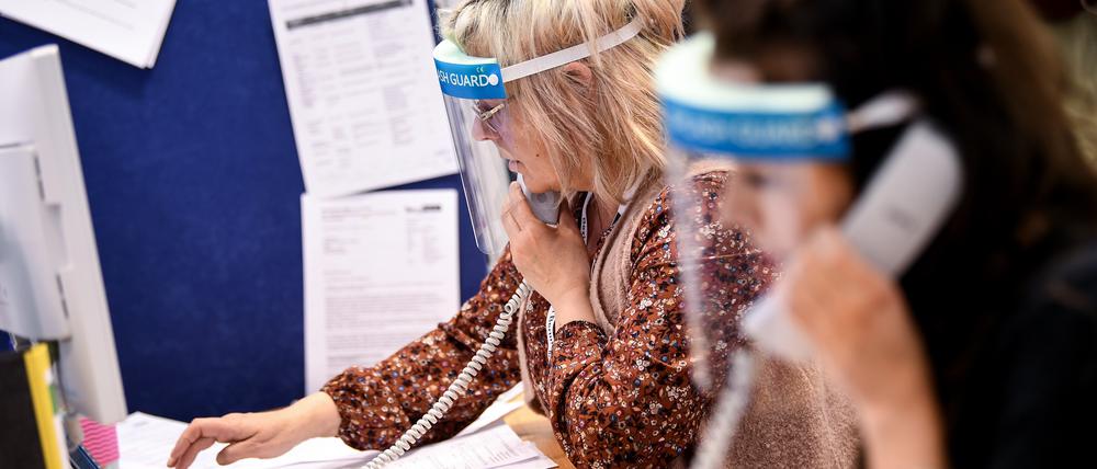 27.04.2020, Berlin: Mitarbeiter des Gesundheitsamtes Mitte mit Gesichtsschutzschirm telefonieren im Lagezentrum des Gesundheitsamt Mitte. Das Gesundheitsamt Mitte führt eine neue Software-Lösung (Kontaktpersonen-Management-System SORMAS -Surveillance and Outbreak Response Management System) für die professionelle Verwaltung von Infektionsfällen ein. Foto: Britta Pedersen/dpa-Zentralbild/dpa +++ dpa-Bildfunk +++ | Verwendung weltweit