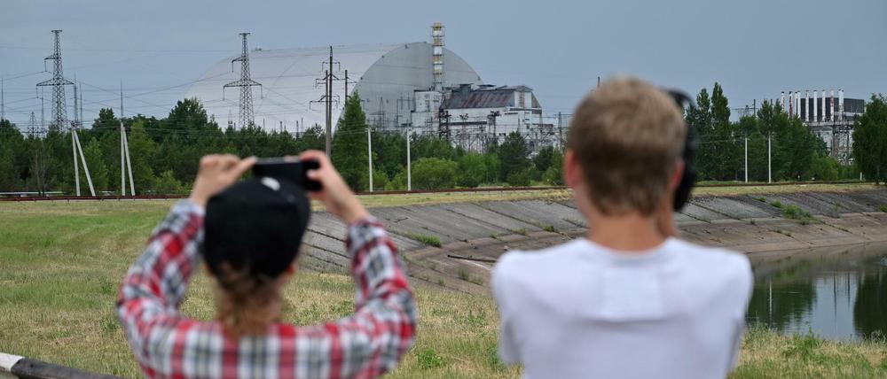 Besucher der Sperrzone fotografieren den von einem Sarkophag ummantelten Reaktor von Tschernobyl.