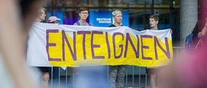 Demonstrantinnen stehen am Morgen vor dem Eingang zur Hauptversammlung des Immobilienkonzerns Deutsche Wohnen und fordern auf einem Transparent "Enteignung".