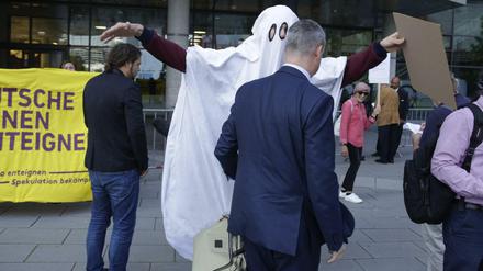 Ein Aktivist im Gespenster-Kostüm "erschreckt" einen Aktionär auf dem Weg zur Hauptversammlung der Deutsche Wohnen SE in Frankfurt am Main am 18. Juni 2019.