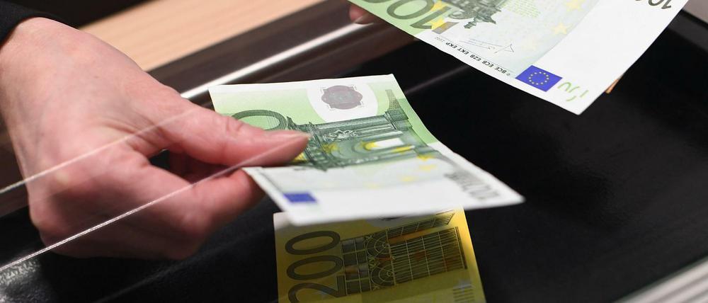 Eine Frau lässt sich in einer Bankfiliale am Schalter Bargeld auszahlen