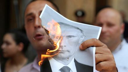 Ein Demonstrant in Tiflis verbrennt ein Foto des russischen Präsidenten Putin. 
