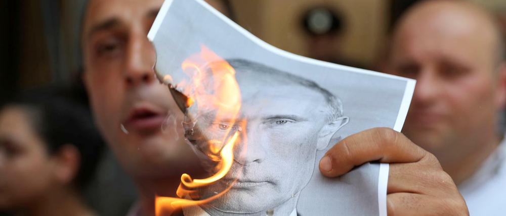 Ein Demonstrant in Tiflis verbrennt ein Foto des russischen Präsidenten Putin.