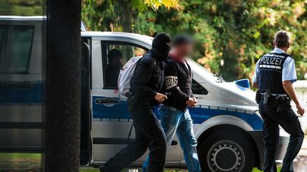 Einer der mutmaßlichen Rechtsterroristen, die in Bayern und Sachsen festgenommen wurden, erreicht den Bundesgerichtshof und wird von Polizisten abgeführt. 